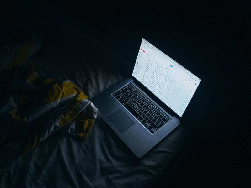 laptop on bed in dark room