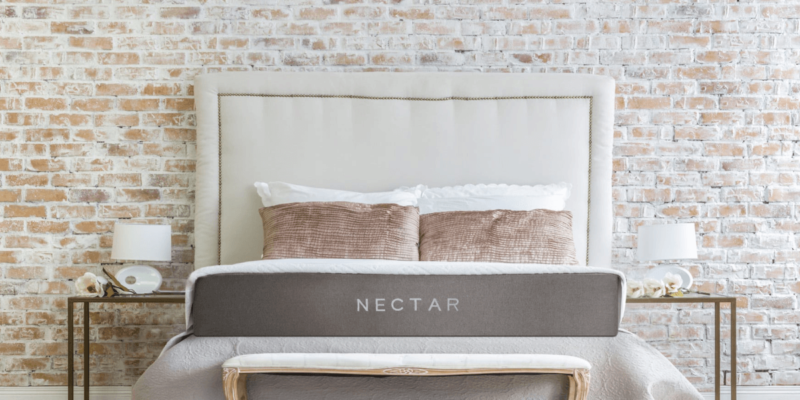 Nectar mattress set up with two bedside table against a brick wall