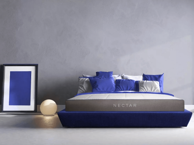 Nectar mattress with blue and gray pillows and blue foundation, on gray background