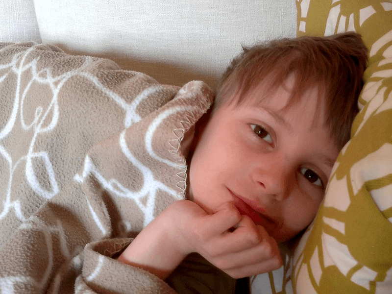 A smiling kid, wide awake on bed