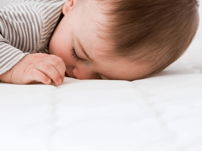 Baby lying face down on Newton Wovenaire crib mattress