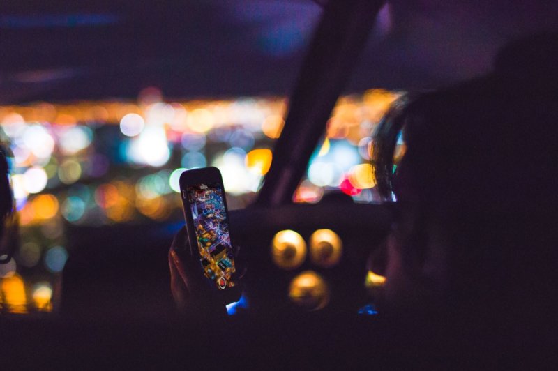 Person using smartphone in the dark with city lights in the background
