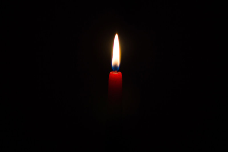 Lone candlelight in darkness