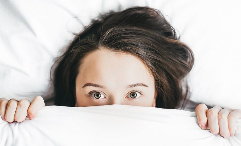 Woman lying under the covers with eyes open