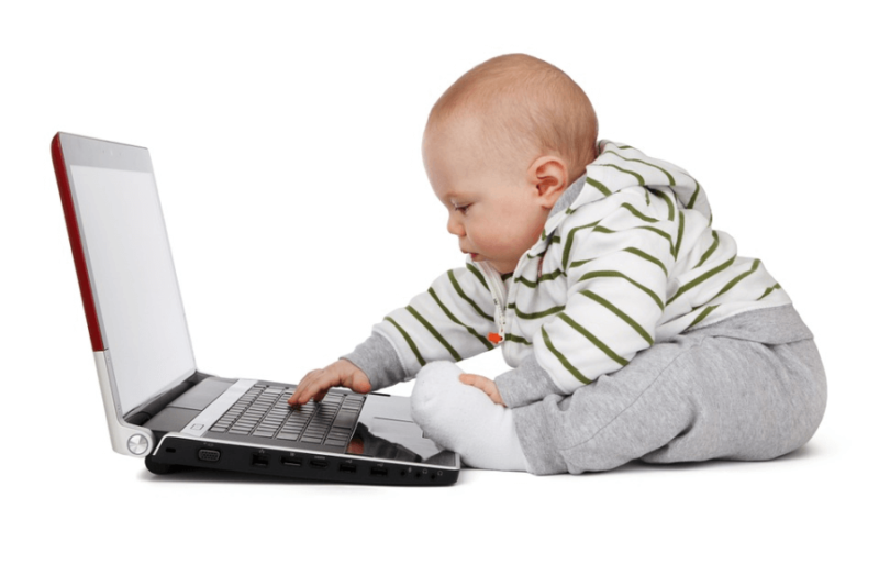 A chubby baby fiddling with a laptop