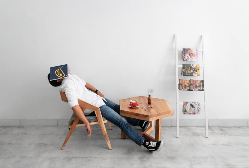 man slumped on a chair, asleep with book over face