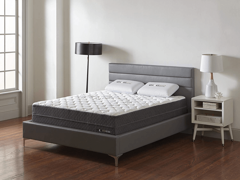 three fourths view of GhostBed Luxe mattress on bedframe between floor lamp and bedside table with lamp