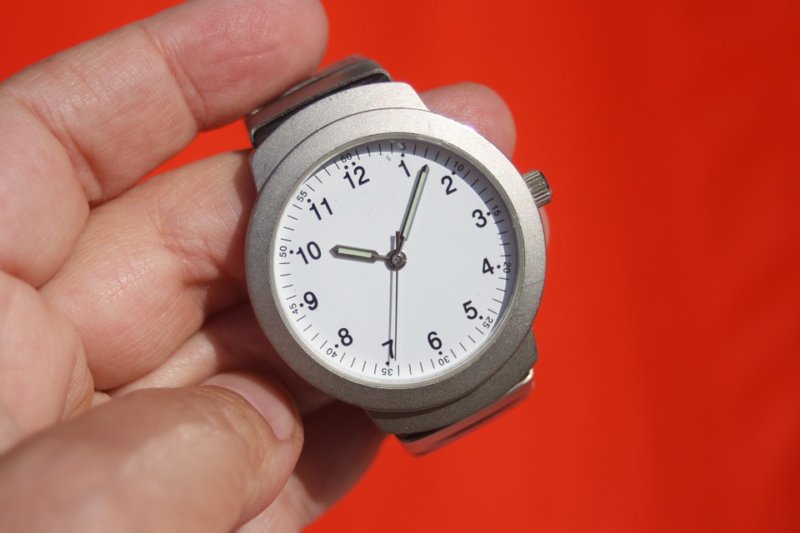 hand holding wristwatch on red background